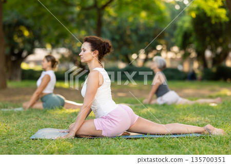 Adult woman doing yoga in pigeon pose Adult woman doing yoga in pigeon pose 135700351