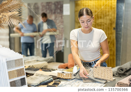 Young woman choosing carpet samples in store Young woman choosing carpet samples in store 135700366