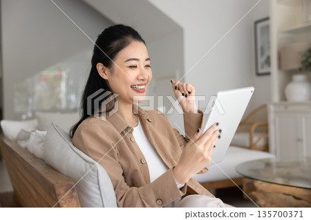 Asian woman read great news on tablet 135700371