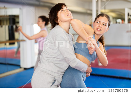 Women practice self-defense techniques in pairs Women practice self-defense techniques in pairs 135700376