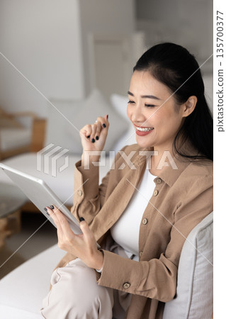 Smiling Vietnamese woman spend time on internet using digital tablet Smiling Vietnamese woman spend time on internet using digital tablet 135700377