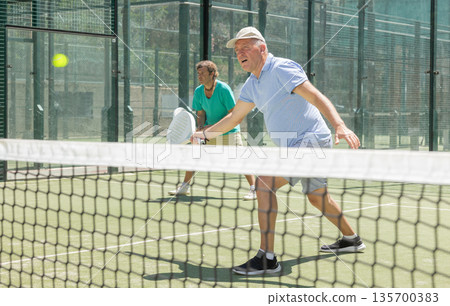 Elderly and adult men playing doubles padel 135700383