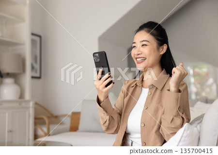 Woman holds smartphone, read notice with cheerful expression Woman holds smartphone, read notice with cheerful expression 135700415