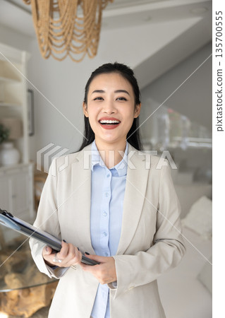Portrait of happy female realtor posing in modern living room 135700555