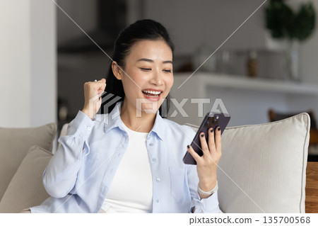 Happy Asian woman read great news on smartphone 135700568