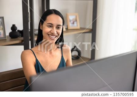 Happy young Indigenous freelancer girl working at large monitor Happy young Indigenous freelancer girl working at large monitor 135700595