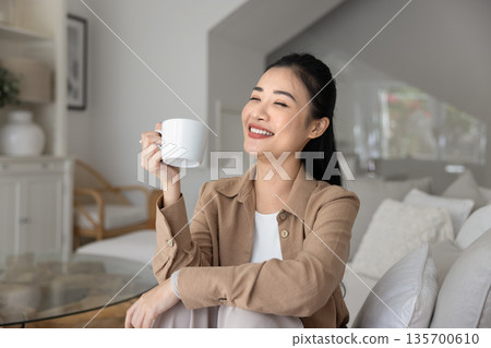 Woman relaxing on sofa with cup of morning tea 135700610