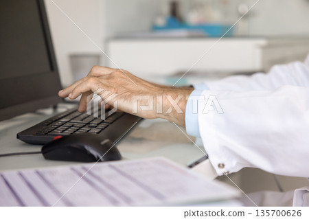 Hands of doctor typing on keyboard at desktop monitor Hands of doctor typing on keyboard at desktop monitor 135700626