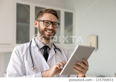 Happy doctor man typing on digital gadget, Happy doctor man typing on digital gadget, 135700653