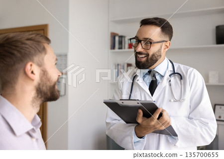 Cheerful doctor man talking to male patient in clinic office Cheerful doctor man talking to male patient in clinic office 135700655