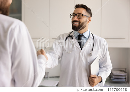 Happy doctor man giving handshake to male coworker Happy doctor man giving handshake to male coworker 135700658