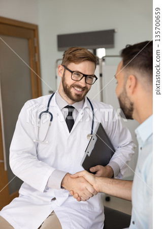 Happy handsome practitioner man giving handshake to healthy patient Happy handsome practitioner man giving handshake to healthy patient 135700659