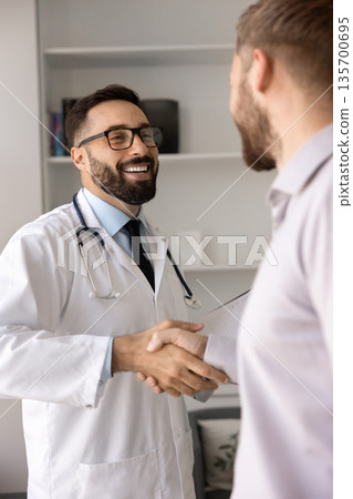 Happy confident Hispanic physician giving handshake to patient 135700695