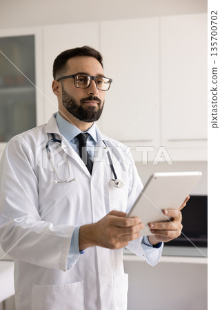 Positive handsome Latin medical practitioner man t using tablet computer 135700702