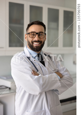 Cheerful young Hispanic doctor man posing for professional vertical portrait 135700703