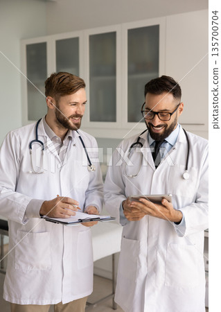 Positive male medical coworkers talking in hospital office Positive male medical coworkers talking in hospital office 135700704