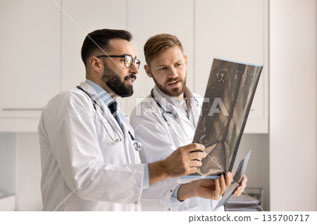 Two neurology doctors looking at X-ray against light 135700717