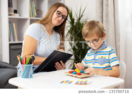 Child Engaged in Educational Activity with Teacher in Classroom Setting 135700718