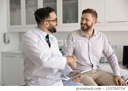 Happy male doctor and patient shaking hands Happy male doctor and patient shaking hands 135700724