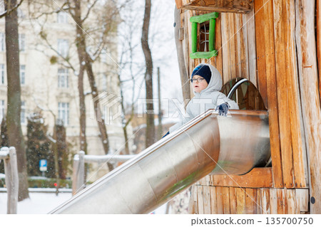 Child Enjoying Winter Slide in Snowy Playground Child Enjoying Winter Slide in Snowy Playground 135700750