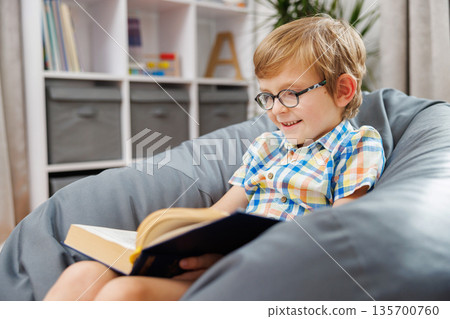 Smiling Child Reading a Book in Cozy Home Setting Smiling Child Reading a Book in Cozy Home Setting 135700760