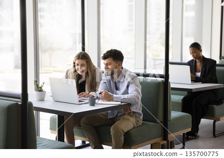 Multicultural businesspeople work on notebooks at tables in coworking area 135700775