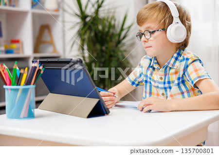 Young Boy Learning Online with Tablet and Headphones at Home 135700801