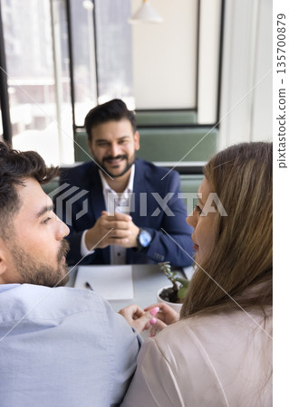 Smiling bank manager wait as clients discuss loan proposal 135700879