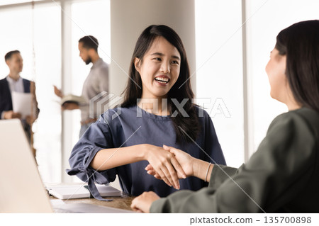 Happy young Asian entrepreneur woman giving handshake to business partner Happy young Asian entrepreneur woman giving handshake to business partner 135700898