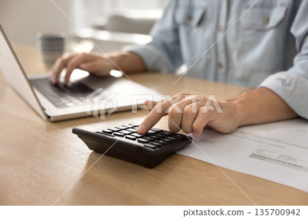 Close up cropped shot businessman hands using notebook and calculator Close up cropped shot businessman hands using notebook and calculator 135700942