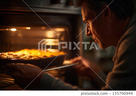 Chef Carefully Sliding Lasagna into Oven with Warm Glow and Anticipation 135700949