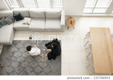 Happy Arabian mother little son constructing from blocks on carpet 135700955