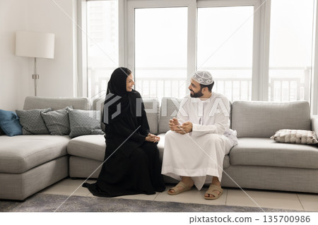 Smiling Arab family couple relaxing talking at home on weekend Smiling Arab family couple relaxing talking at home on weekend 135700986