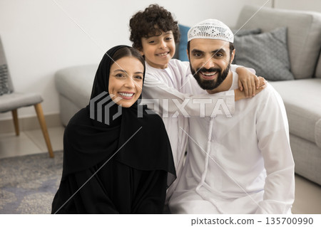 Happy Arabic couple with schoolboy son cuddle at living room Happy Arabic couple with schoolboy son cuddle at living room 135700990