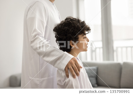 Little Arabic boy looking forward feeling dad hand on shoulder Little Arabic boy looking forward feeling dad hand on shoulder 135700991