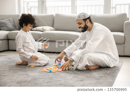 Friendly Arabian dad play constructor with little son on floor 135700995