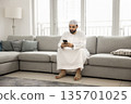 Young Arabian man using phone on couch at living room 135701025