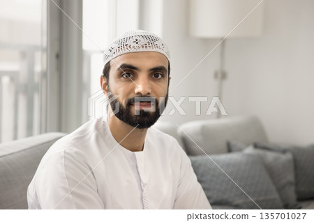 Young Middle-Eastern man in traditional Muslim wear looking at camera 135701027