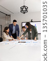 Four multiethnic colleagues analyze data in meeting room 135701035