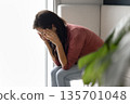 Sad woman covering face in despair seated indoors 135701048
