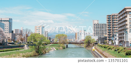 Beautiful Iwate mountain and Kitakami river with flowers blooming in Spring season, cityscape against blue sky in Morioka city, Iwate prefecture, Japan. Iwate, Japan, 24 April 2025 135701101