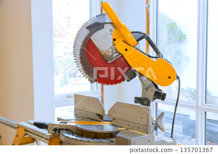 Table saw sits in saw has circular blade ready for cutting wood, tools materials surround area busy work environment. Table saw sits in saw has circular blade ready for cutting wood, tools materials surround area busy work environment. 135701367