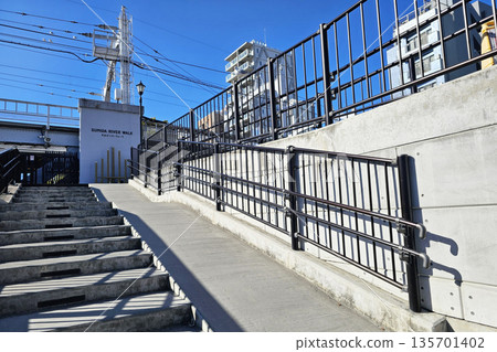 Entrance to the Sumida River Walk pedestrian pathway with stairs and ramp on a sunny day. Entrance to the Sumida River Walk pedestrian pathway with stairs and ramp on a sunny day. 135701402