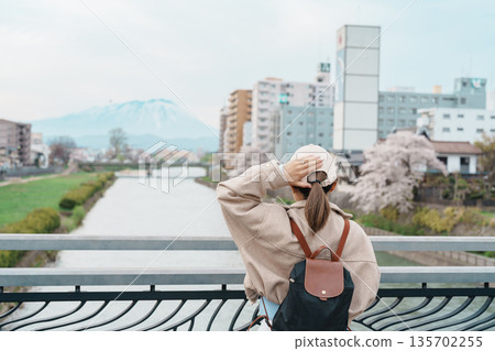 Woman tourist sightseeing Iwate mountain and Kitakami river with flowers in Spring, happy traveler travel in Morioka city, Iwate prefecture, Japan. famous Landmark Travel and Vacation destination 135702255