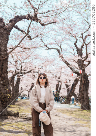 Woman tourist sightseeing Goryokaku Tower park with Sakura Cherry Blossom in Spring, happy traveler travel in Hakodate city, Hokkaido, Japan. famous Landmark, Japan Travel and Vacation destination 135702296