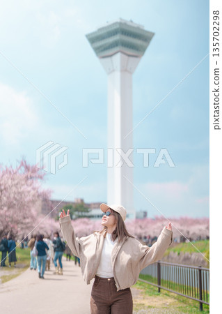 Woman tourist sightseeing Goryokaku Tower park with Sakura Cherry Blossom in Spring, happy traveler travel in Hakodate city, Hokkaido, Japan. famous Landmark, Japan Travel and Vacation destination 135702298