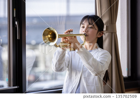 Elementary school student playing the trumpet Elementary school student playing the trumpet 135702509