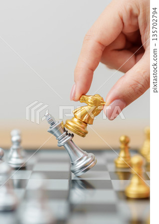 hand moving gold Chess knight figure and Checkmate opponent during chessboard competition. Strategy, Success, management, business planning, win, disruption, Trade war and leadership concept hand moving gold Chess knight figure and Checkmate opponent during chessboard competition. Strategy, Success, management, business planning, win, disruption, Trade war and leadership concept 135702794