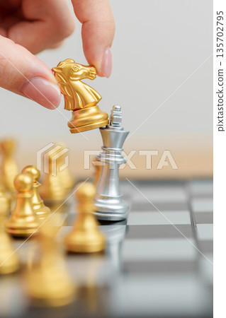 hand moving gold Chess knight figure and Checkmate opponent during chessboard competition. Strategy, Success, management, business planning, win, disruption, Trade war and leadership concept hand moving gold Chess knight figure and Checkmate opponent during chessboard competition. Strategy, Success, management, business planning, win, disruption, Trade war and leadership concept 135702795