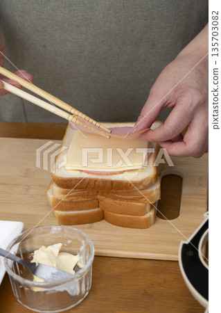 Hands making a hot sandwich with a hot sandwich maker Hands making a hot sandwich with a hot sandwich maker 135703082